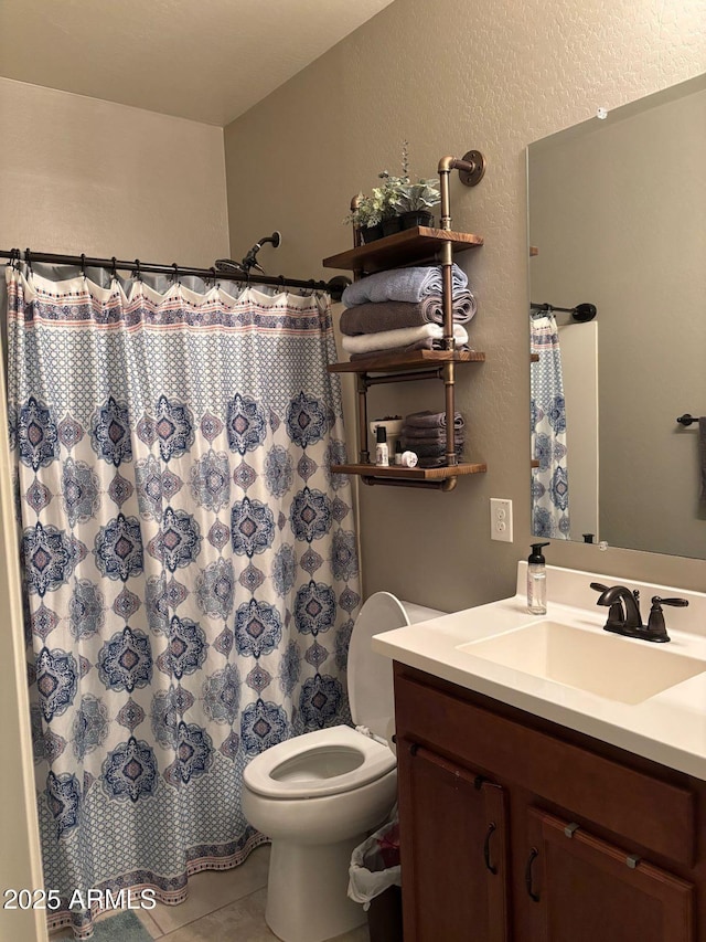 bathroom with tile patterned floors, a shower with curtain, toilet, vanity, and a textured wall