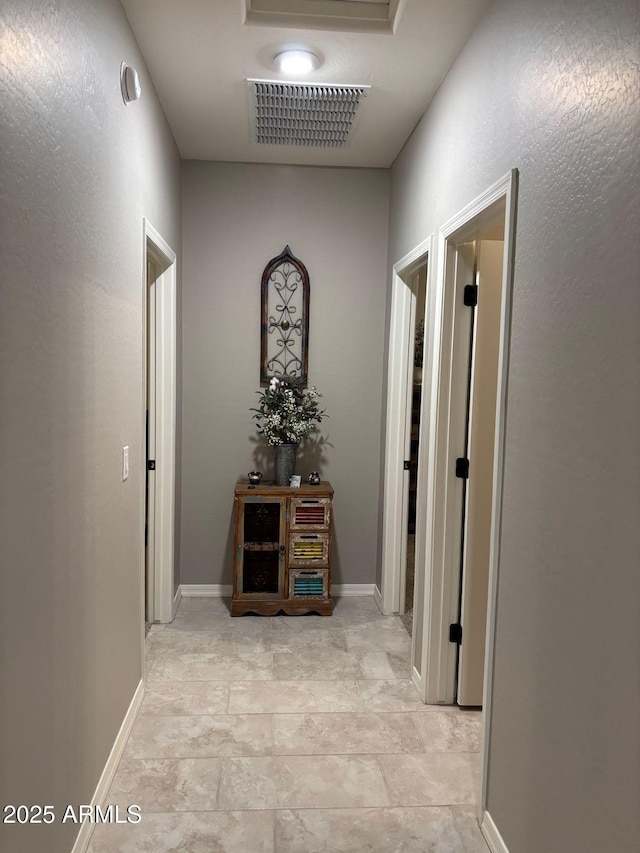 hall featuring visible vents and baseboards