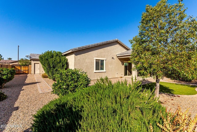 view of property exterior with a patio area, stucco siding, and fence