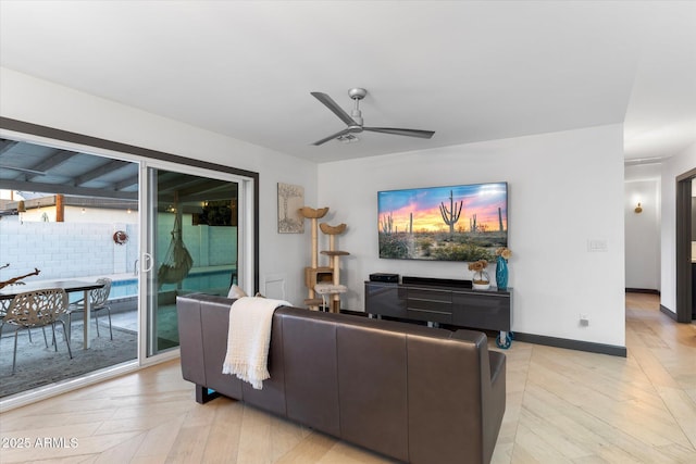 living room with light wood finished floors, a ceiling fan, and baseboards