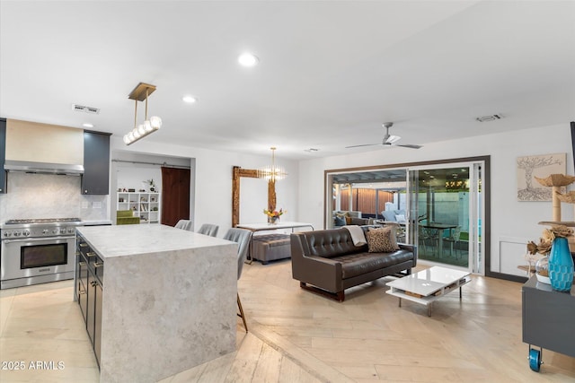 kitchen featuring tasteful backsplash, visible vents, high end range, and wall chimney exhaust hood