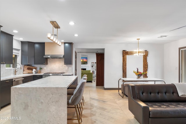 kitchen featuring tasteful backsplash, visible vents, a center island, hanging light fixtures, and light stone countertops