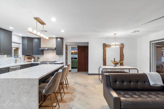 kitchen with visible vents, appliances with stainless steel finishes, a kitchen breakfast bar, wall chimney range hood, and backsplash