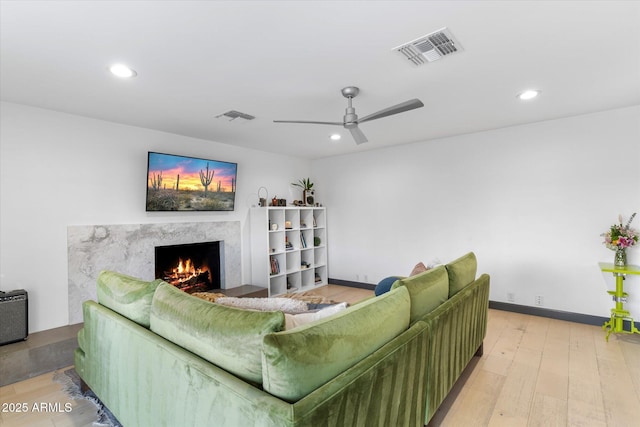 living room with light wood-type flooring, visible vents, a fireplace, and recessed lighting