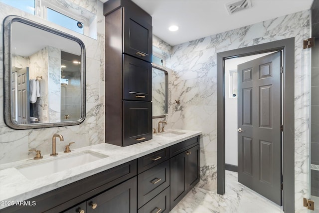 bathroom with marble finish floor, tile walls, visible vents, and a sink