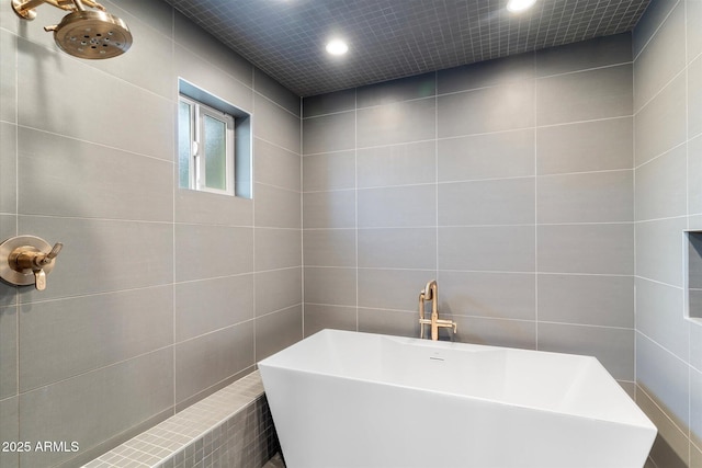 full bath featuring recessed lighting, a freestanding bath, and tile walls