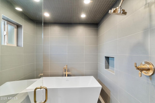 bathroom with a freestanding tub, tile walls, and recessed lighting