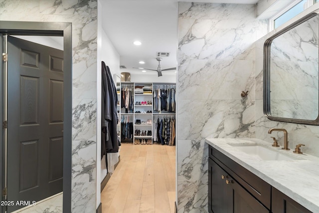 bathroom featuring recessed lighting, vanity, visible vents, tile walls, and a spacious closet