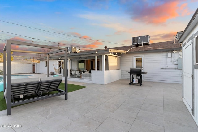 patio terrace at dusk featuring central AC, an outdoor pool, and area for grilling