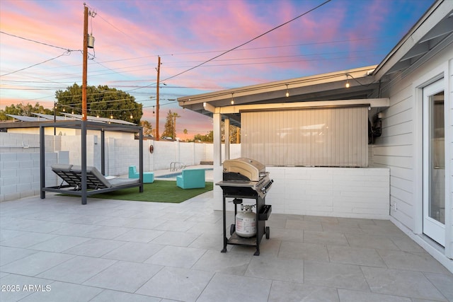 patio terrace at dusk featuring fence and grilling area