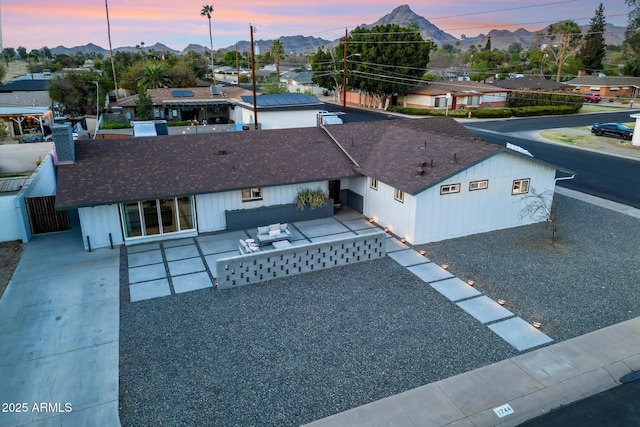 exterior space featuring a chimney, a shingled roof, a patio area, a mountain view, and fence