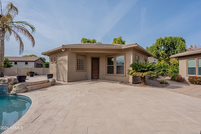 back of house with a fenced in pool and a patio