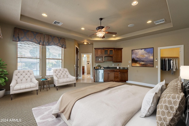 bedroom featuring a spacious closet, ceiling fan, a tray ceiling, light carpet, and a closet