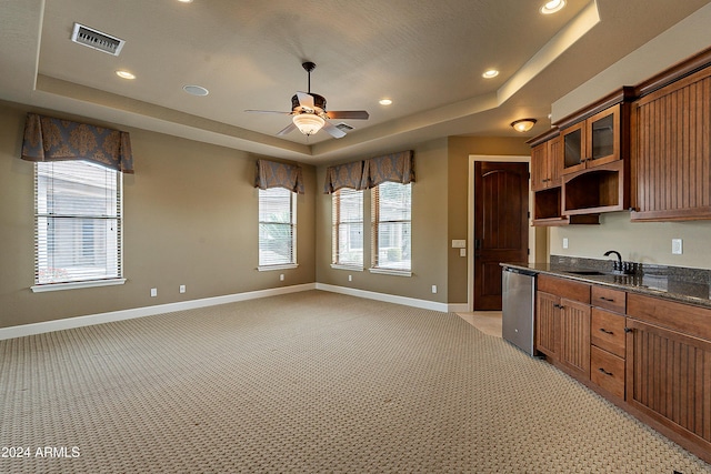 kitchen with a raised ceiling, light carpet, ceiling fan, and stainless steel dishwasher