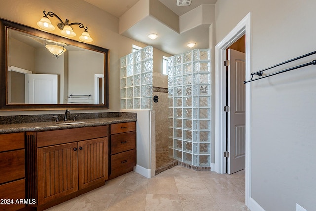 bathroom with a tile shower, vanity, and tile patterned floors