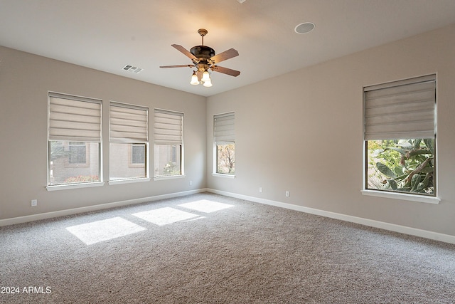 carpeted empty room with ceiling fan and a wealth of natural light