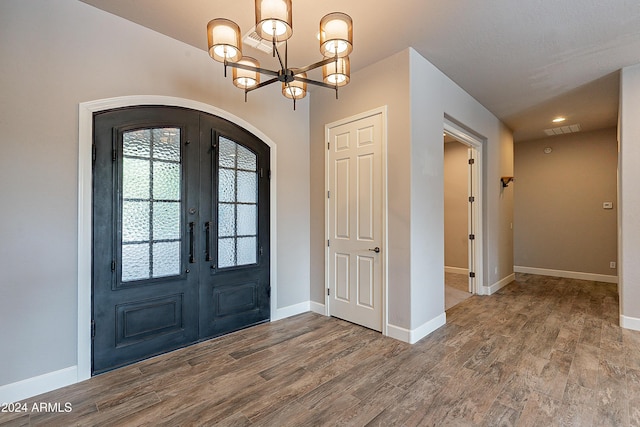 foyer featuring an inviting chandelier, wood-type flooring, and french doors