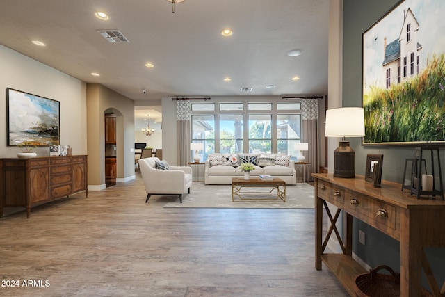 living room with light hardwood / wood-style floors and an inviting chandelier