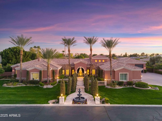 mediterranean / spanish house featuring a front yard, driveway, and stucco siding