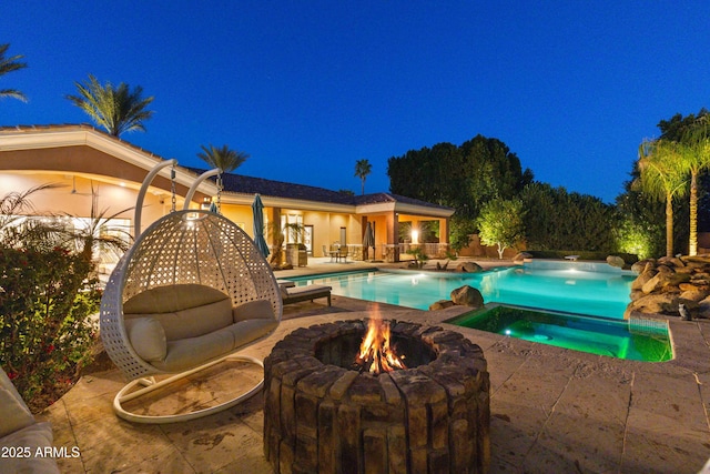 pool at night featuring a patio area and an outdoor pool