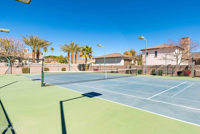 view of tennis court with community basketball court and fence