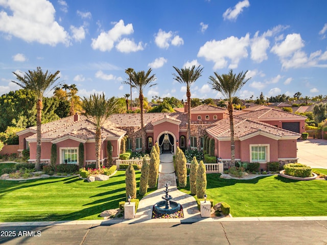 mediterranean / spanish house featuring a tiled roof, a front lawn, and stucco siding