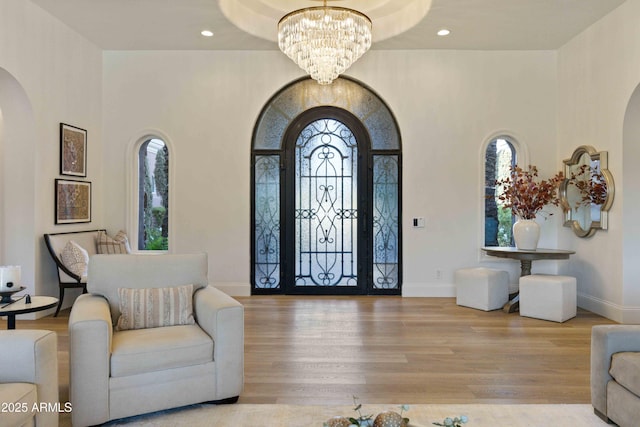 entryway featuring arched walkways, a chandelier, recessed lighting, wood finished floors, and baseboards