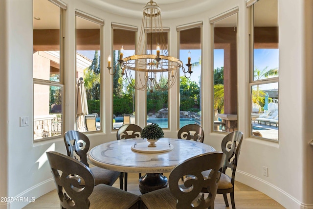 dining area featuring light wood finished floors, baseboards, and an inviting chandelier