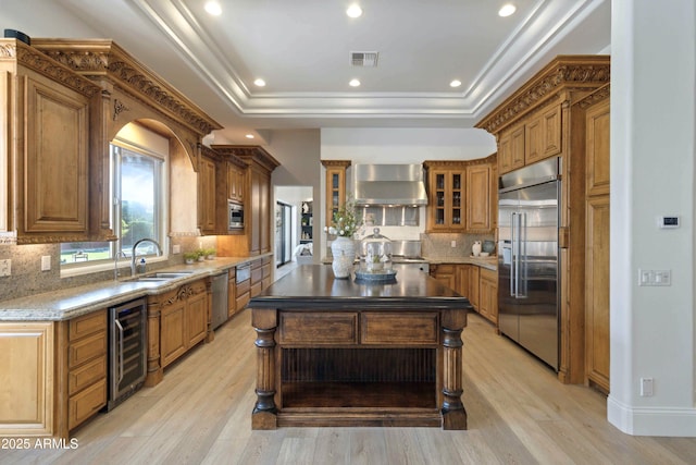 kitchen featuring beverage cooler, a sink, appliances with stainless steel finishes, wall chimney exhaust hood, and a raised ceiling