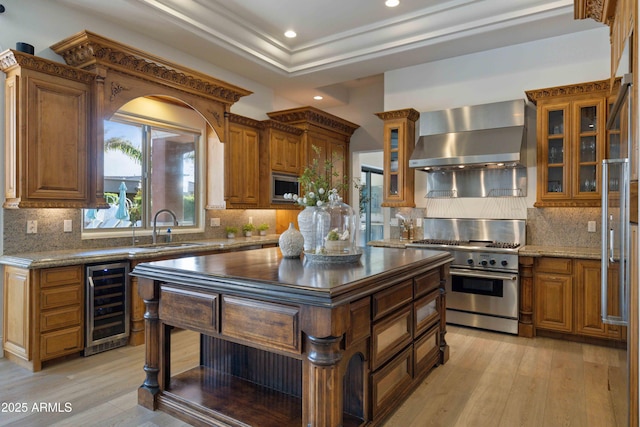 kitchen featuring wall chimney exhaust hood, wine cooler, a tray ceiling, stainless steel stove, and a sink