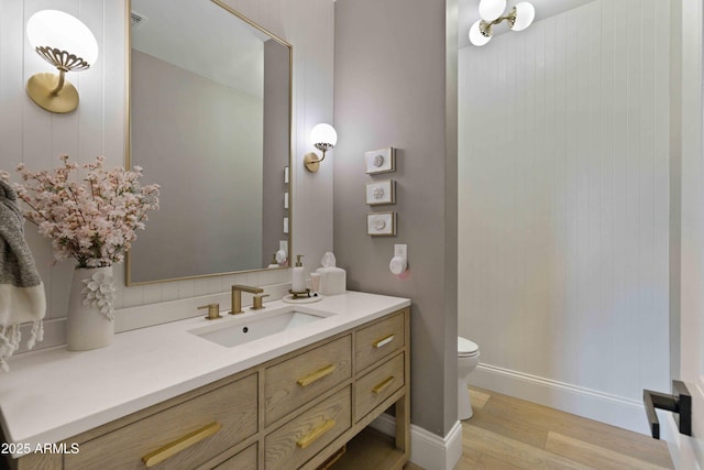 bathroom featuring baseboards, vanity, toilet, and wood finished floors