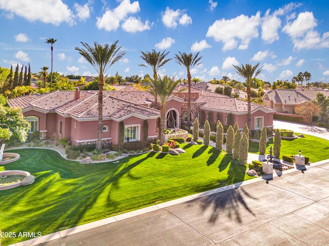 mediterranean / spanish-style home featuring a tiled roof, a front yard, a residential view, and stucco siding