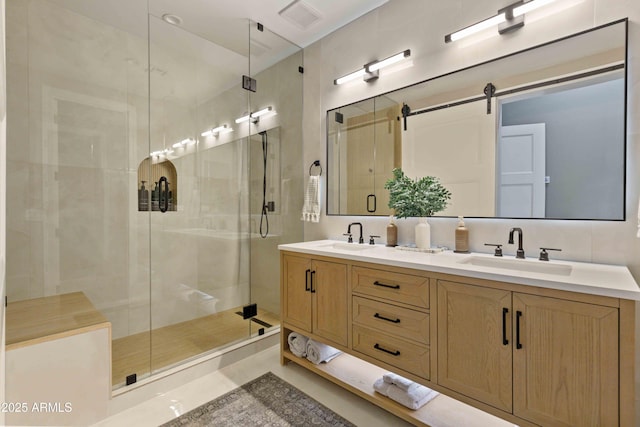 bathroom with a stall shower, visible vents, a sink, and double vanity