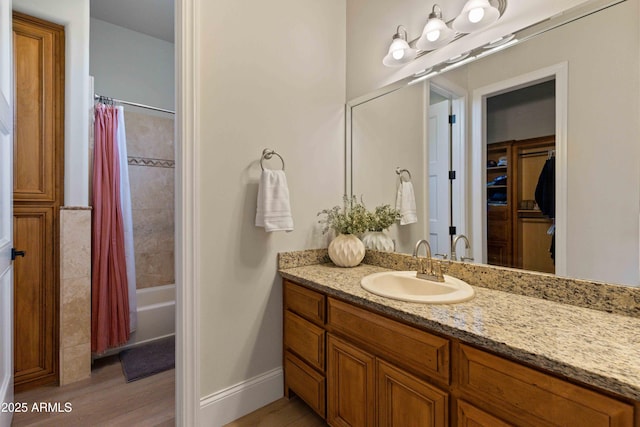 full bathroom with baseboards, shower / bath combo with shower curtain, wood finished floors, and vanity