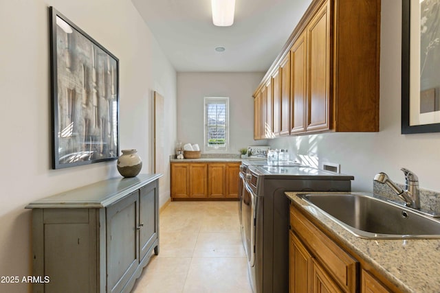 kitchen featuring brown cabinets, washing machine and clothes dryer, light countertops, light tile patterned flooring, and a sink