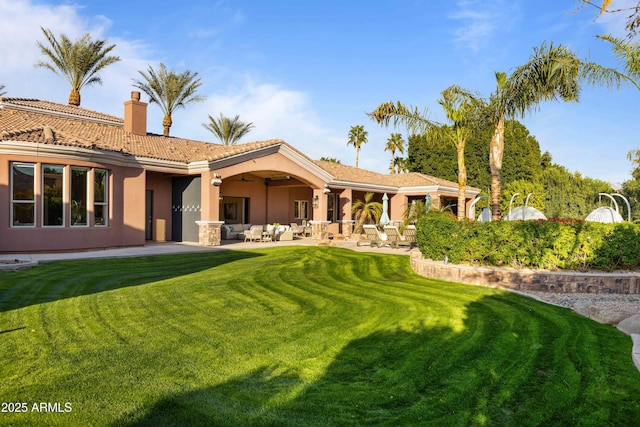 back of house with an outdoor living space, a lawn, stucco siding, a chimney, and a patio area