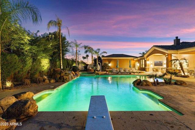 outdoor pool featuring a patio and a diving board