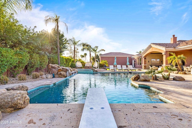 pool with a diving board and a patio area