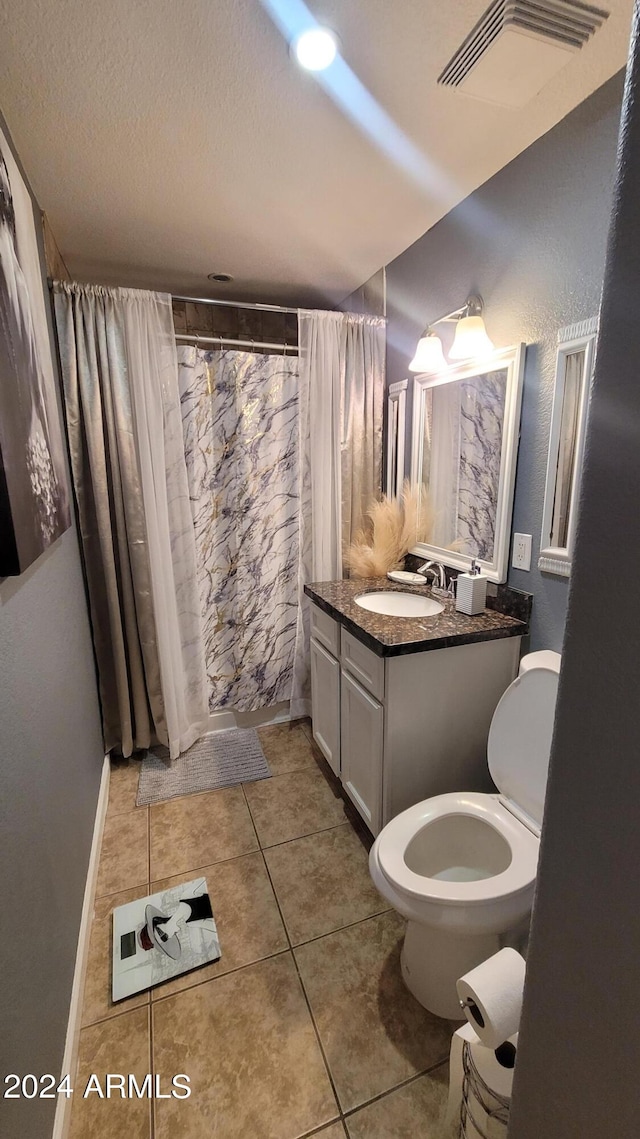 bathroom with vanity, tile patterned flooring, toilet, and a textured ceiling