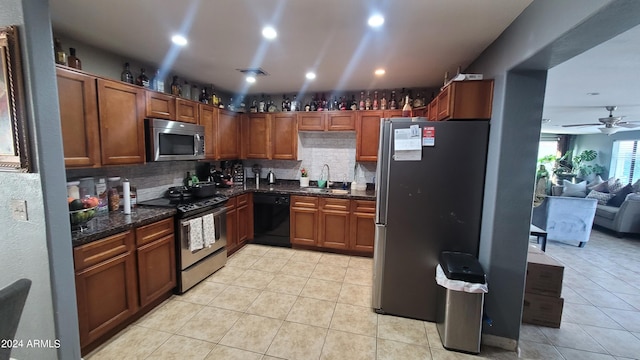 kitchen featuring light tile patterned floors, ceiling fan, appliances with stainless steel finishes, decorative backsplash, and sink