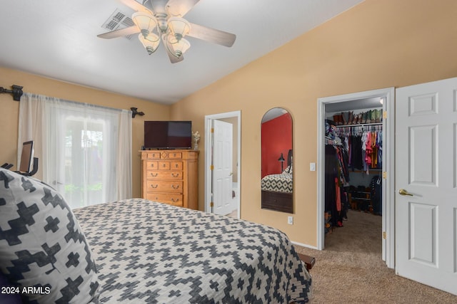 carpeted bedroom featuring a walk in closet, vaulted ceiling, a closet, and ceiling fan