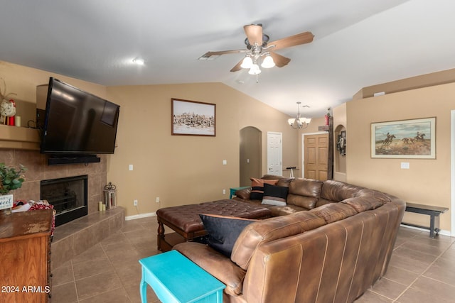 tiled living room with lofted ceiling, a fireplace, and ceiling fan with notable chandelier