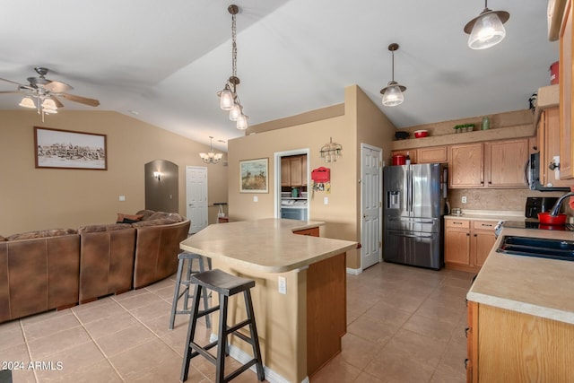 kitchen with appliances with stainless steel finishes, decorative light fixtures, vaulted ceiling, and a breakfast bar area