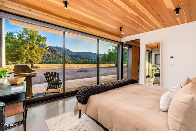 bedroom featuring a mountain view, multiple windows, wood ceiling, and access to exterior