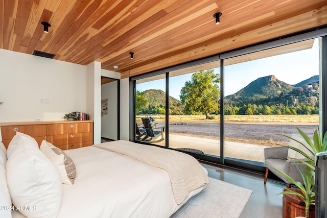 bedroom featuring a mountain view, access to exterior, concrete flooring, and wooden ceiling