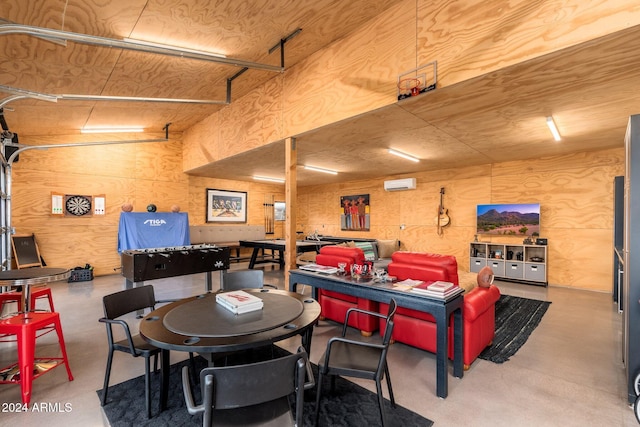 dining space featuring wood walls, a wall mounted AC, and concrete flooring