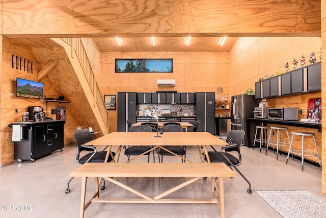 dining area with a wall mounted AC and a towering ceiling