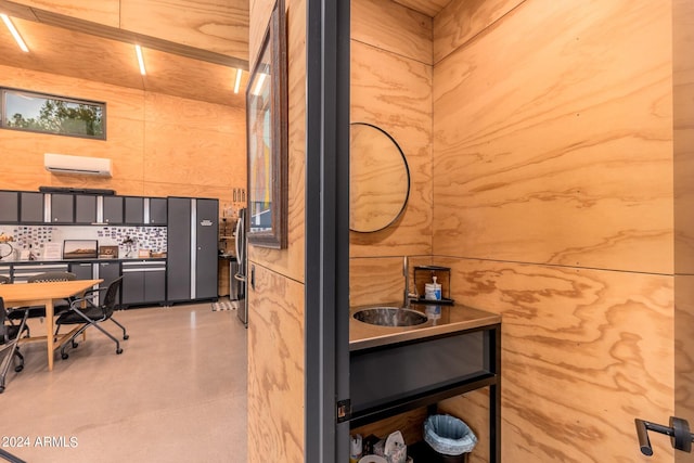 kitchen featuring gray cabinets, wooden walls, a wall mounted AC, and stainless steel refrigerator