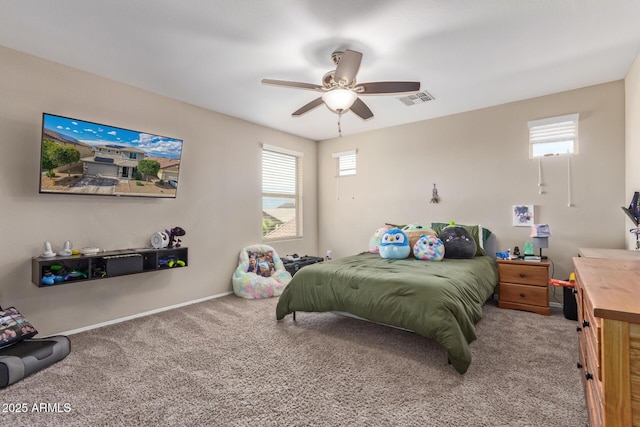 carpeted bedroom featuring a ceiling fan, baseboards, visible vents, and multiple windows