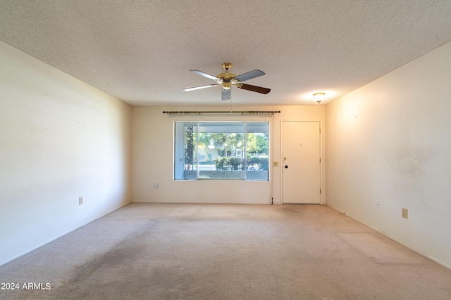 empty room featuring ceiling fan, light colored carpet, and a textured ceiling